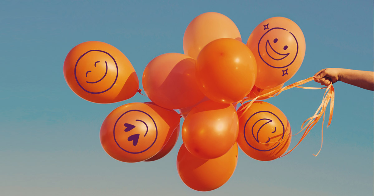 Ein Strauß Luftballons mit Smileys, der in den Himmel fliegt